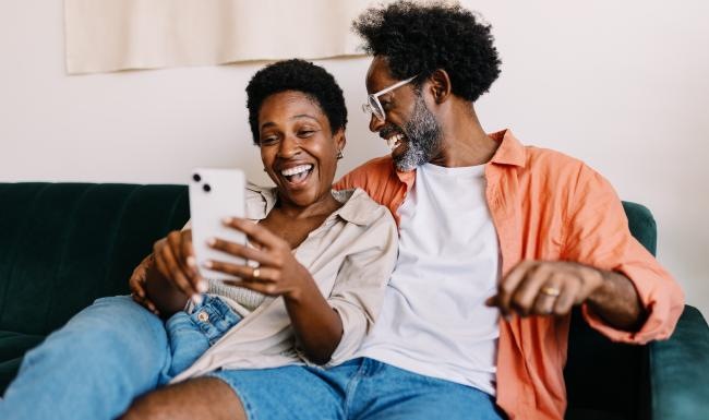 a man and woman sitting on a couch and looking at a phone
